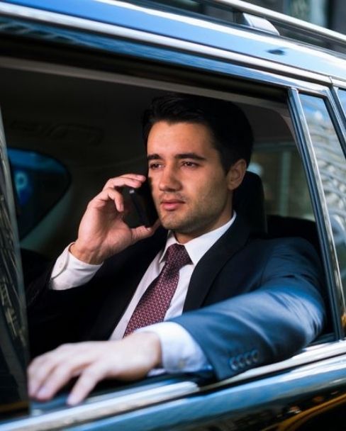 Business Chauffeur Service in Berlin – Geschäftsmann telefoniert in einer luxuriösen Limousine